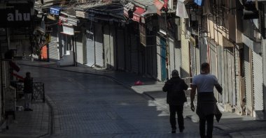 Two men walk by closed stores in a deserted street in Istanbul, Turkey, April 30, 2021. (AFP Photo)