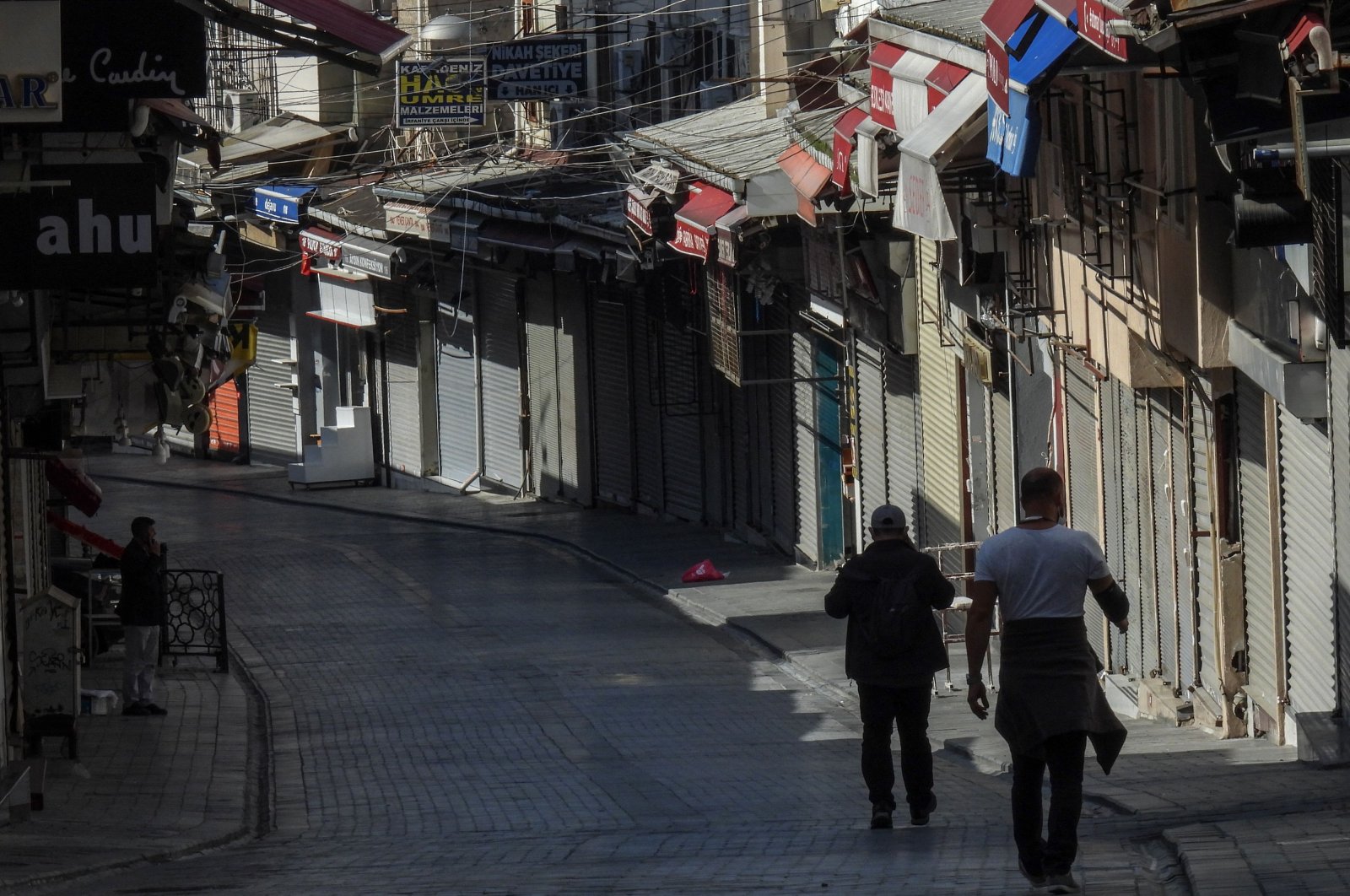 Two men walk by closed stores in a deserted street in Istanbul, Turkey, April 30, 2021. (AFP Photo)