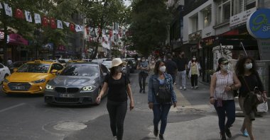 People wearing masks to help protect against the spread of the coronavirus walk near a busy street, two days after a 17-day full lockdown ended, in Ankara, Turkey, May 18, 2021. (AP Photo)
