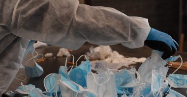 An employee sorts used masks at the Greenwishes waste sorting center in Gennevilliers near Paris on April 19, 2021. (AFP Photo)