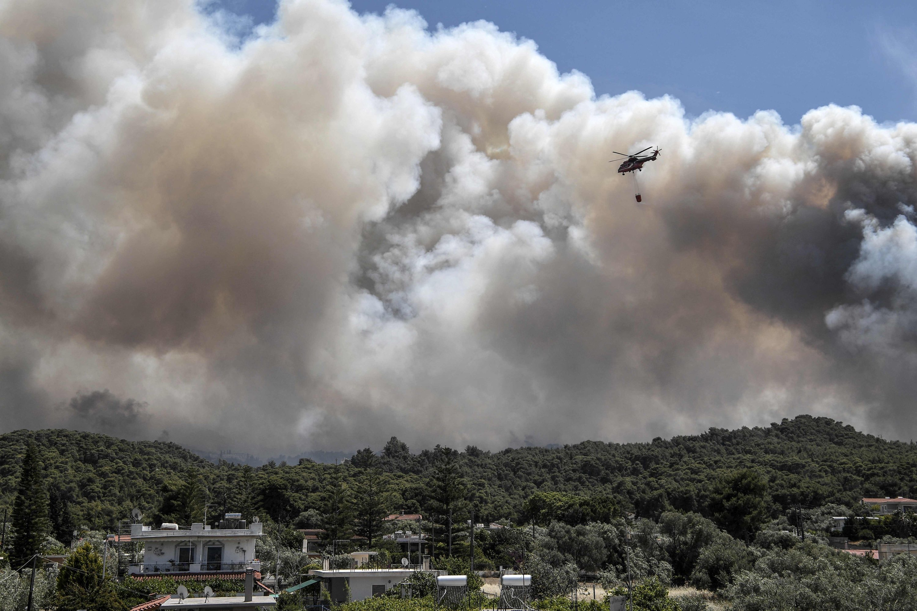 Following an overnight fire on a mountain range overlooking the Gulf of Corinth, a firefighting helicopter flies over the village of Alepochori in Greece, May 20, 2021. (AFP Photo)