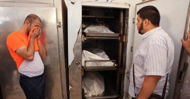 A brother weeps in front of the corpses at the morgue, where Iyad, a 33-year-old wheelchair-bound Palestinian man killed in his house along with his pregnant wife and their 3-year-old daughter during an Israeli airstrike, were trasported, Deir el-Balah, Gaza Strip, Palestine. (AFP Photo)