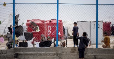 Children cross through an opening in a fence at the al-Hol camp, which houses some 60,000 refugees, including families and supporters of Daesh, in Hasakeh province, Syria, Saturday, May 1, 2021. (AP Photo)