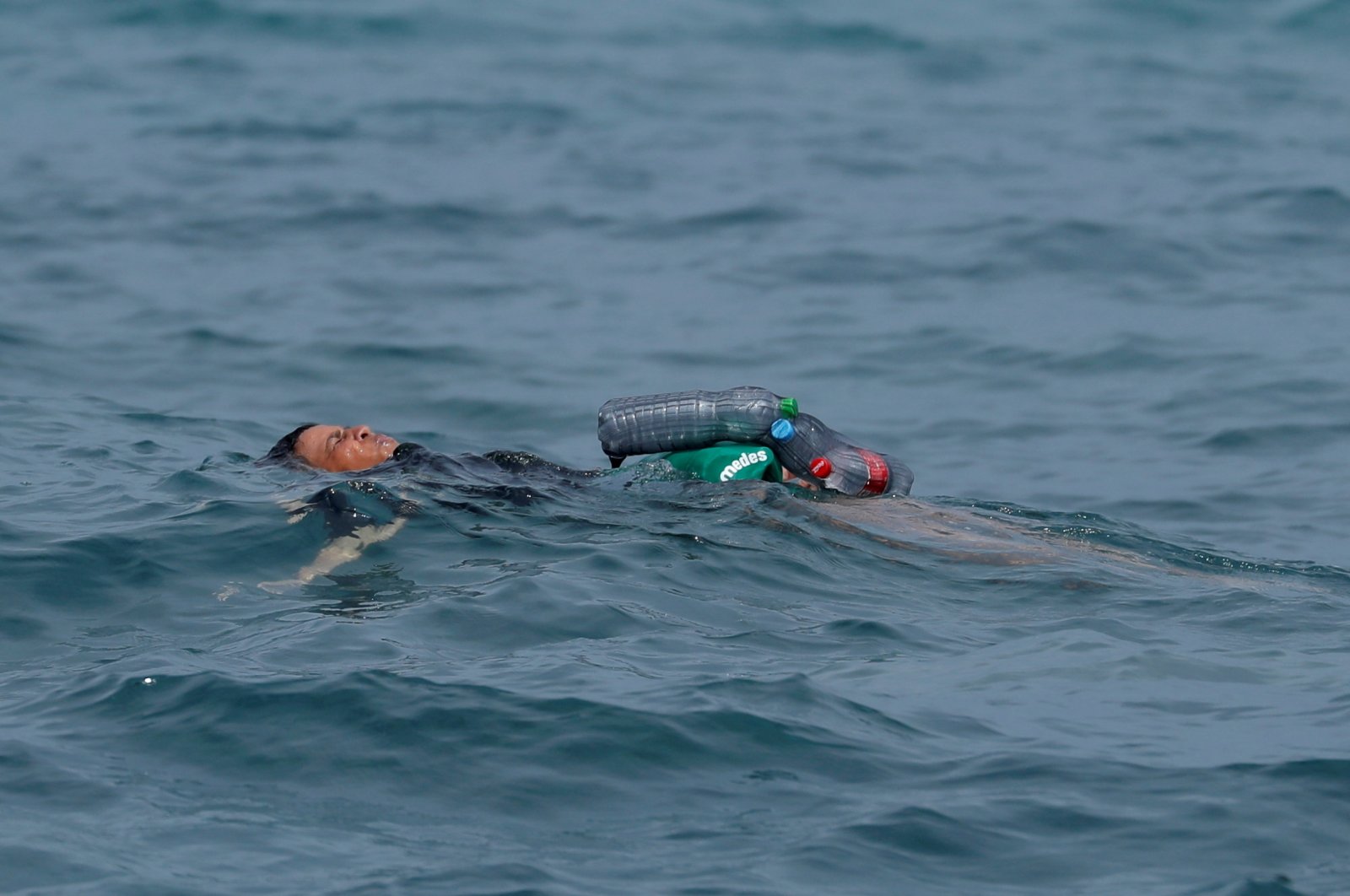 A Moroccan boy swims using bottles as a float, near the fence between the Spanish-Moroccan border, after thousands of migrants swam across the border, in Ceuta, Spain, May 19, 2021. (Reuters Photo)