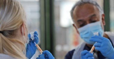 Apprentice nursing associate Ellie Bull (L) and Dr. Anil Mehta prepare syringes with doses of the AstraZeneca vaccine at the Welcome Centre in Ilford, east London, England, Feb. 5, 2021. (AP Photo)
