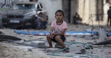 A Palestinian boy sits looking at others inspecting the damage of their shops following Israeli airstrikes on Jabaliya refugee camp, northern Gaza Strip, May 20, 2021. (AP Photo)