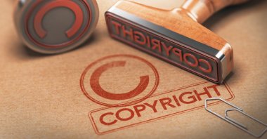 An illustration shows the word “copyright” and the term's symbol, stamped on a paper alongside their corresponding rubber stamps. (Shutterstock Photo)