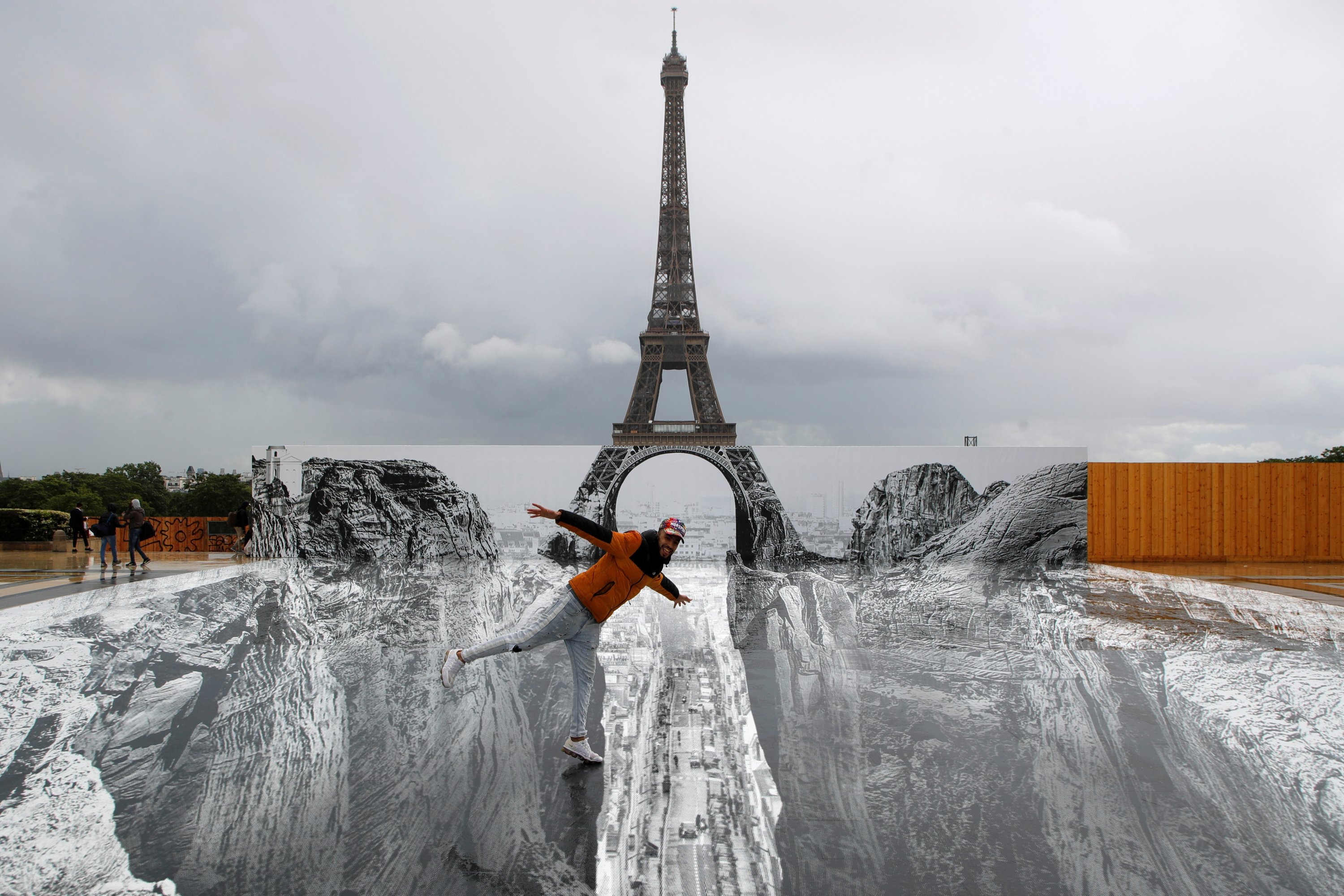 A man poses on giant artwork by French artist JR installed on Trocadero square in front of the Eiffel Tower in Paris, France, May 19, 2021. (Reuters Photo)