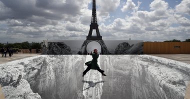 A woman jumps at Trocadero square in front of the Eiffel Tower where French artist and photographer JR set his artwork, in Paris, France, May 21, 2021. (AP Photo)