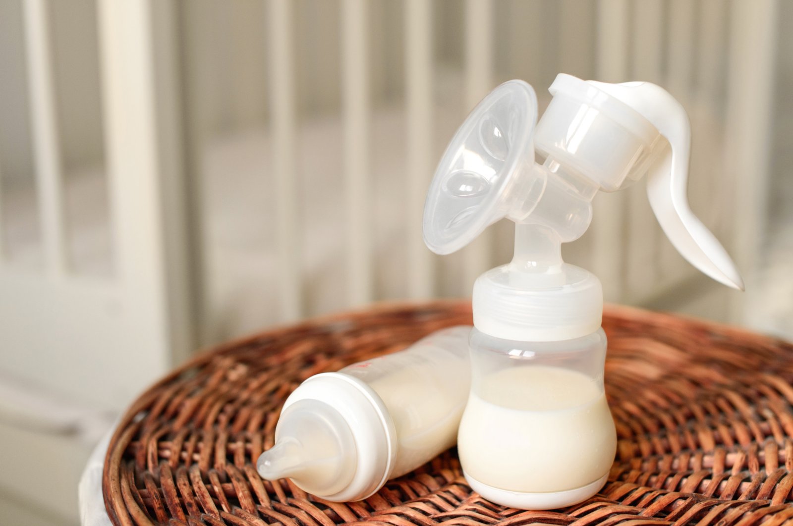 A breast pump and bottle with milk for baby stand on a straw basket. (Getty Images)