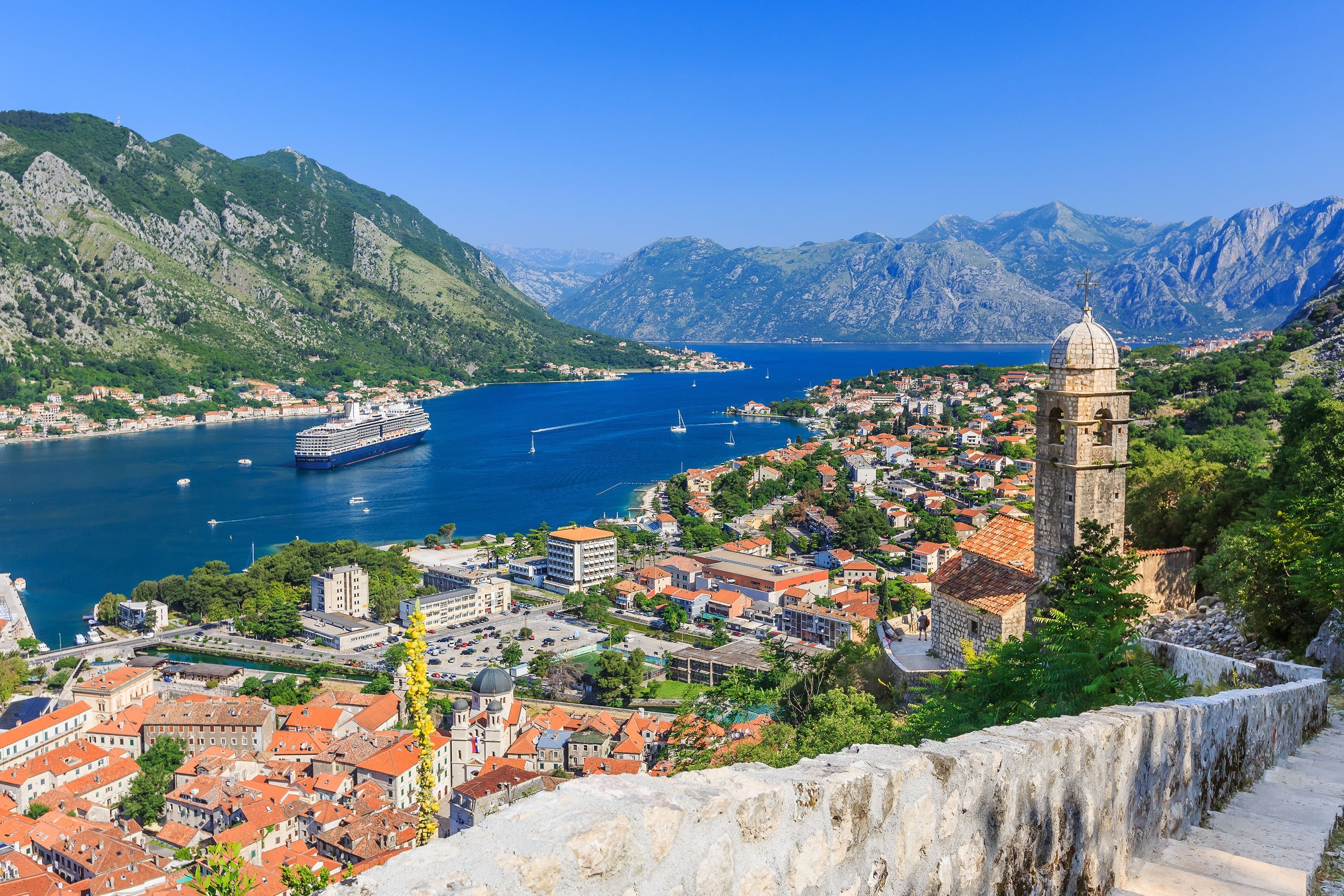 From the skirts of Mount Lovcen, a giant cruise ship approaches the Old Town part of the city of Kotor in Kotor Bay, Montenegro. (Shutterstock Photo)