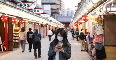 A woman wearing a mask walks through a shopping area of Asakusa Shrine, Tokyo, Japan, March 1, 2021. (Reuters Photo)