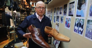 Shomaker Öncel Kalkan poses with the large-size shoes he made in his shop in Beyoğlu, Istanbul, Turkey, May 24, 2021. (AA Photo)