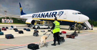 Security with a sniffer dog checks the luggage of passengers in front of the Ryanair Boeing 737-8AS (flight FR4978), carrying opposition figure Roman Protasevich, in Minsk, Belarus, May 23, 2021. (EPA Photo / ONLINER.BY handout photo)