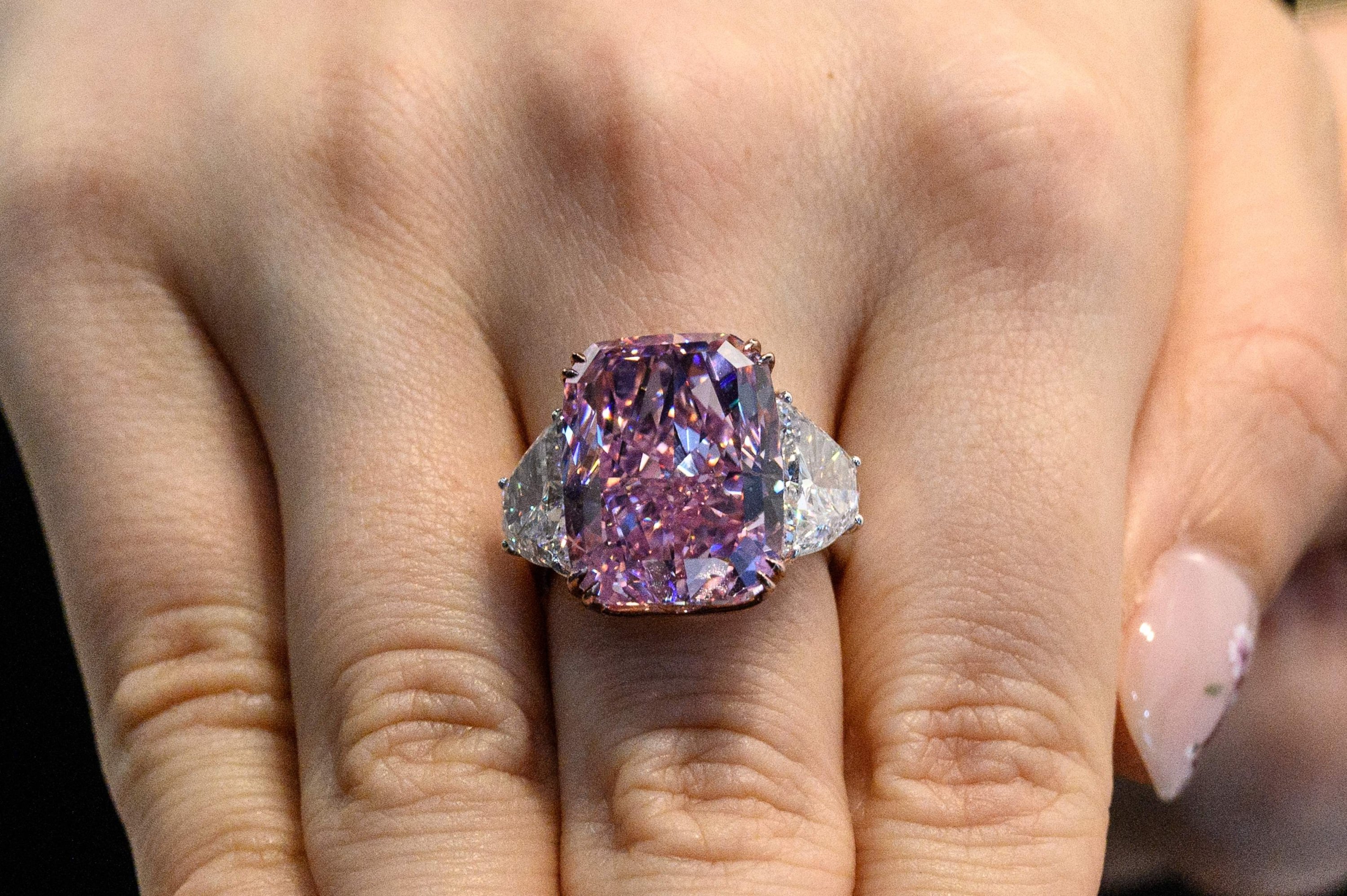 A woman displays the Sakura Diamond, a 15.81 carat fancy vivid purple-pink diamond ring, during a Christies pre-auction preview in Hong Kong, May 20, 2021. (AFP Photo)