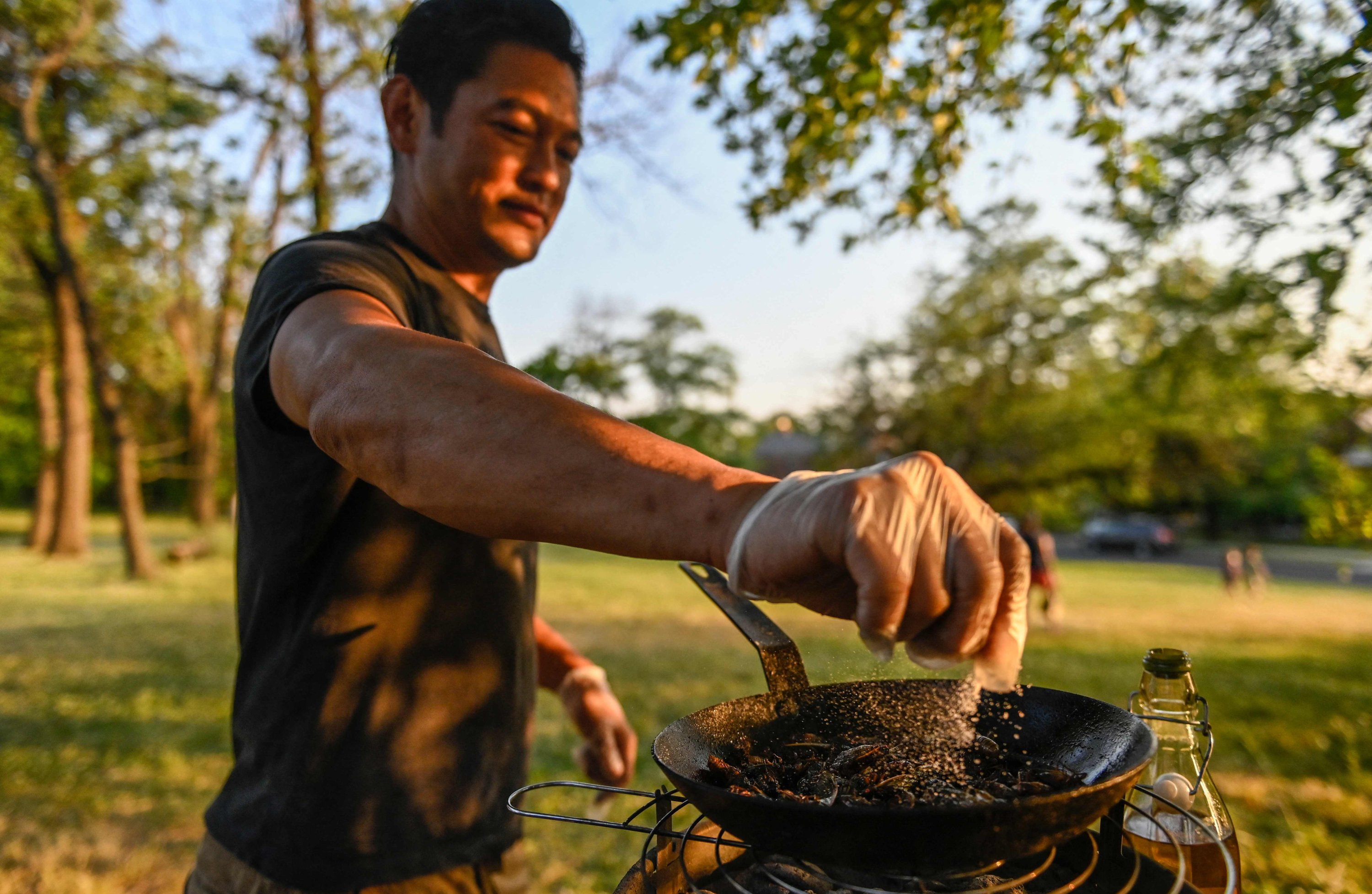 Chef Bun Lai seasons cicadas with salt as he fries them at Fort Totten Park in Washington, U.S., May 23, 2021. (AFP Photo)