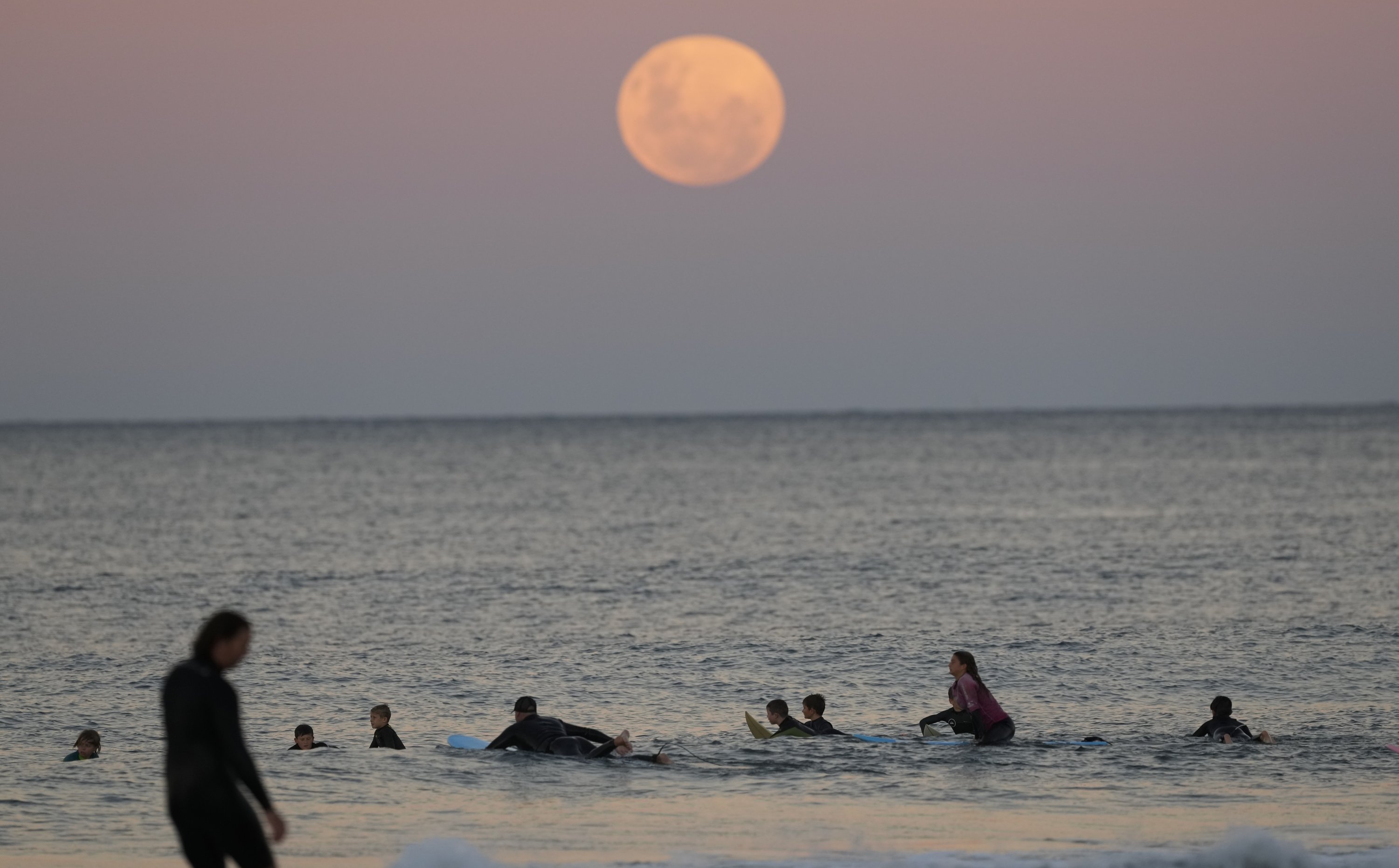 Surfers wait for waves as the moon rises in Sydney, Australia, May 26, 2021. (AP Photo)