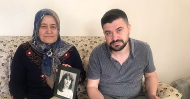 Hatice Özdemir (L) and her son Mümin, who were forced to leave Bulgaria in 1989, show their family album in their home, in Kocaeli, northwestern Turkey, May 21, 2021. (AA PHOTO) 