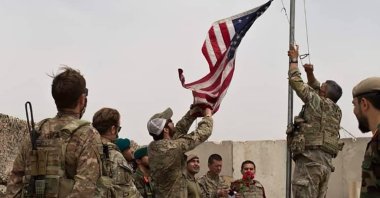A U.S. flag is lowered as American and Afghan soldiers attend a handover ceremony from the U.S. Army to the Afghan National Army, at Camp Anthonic, in Helmand province, southern Afghanistan, May 2, 2021. (AP Photo)