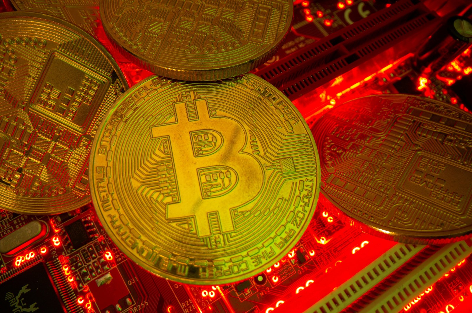 Representations of the virtual currency Bitcoin stand on a motherboard in this picture illustration taken May 20, 2021. (Reuters Photo)