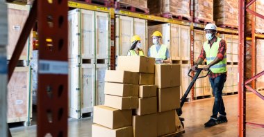 Postal workers in protective masks against the coronavirus work in a warehouse. (Photo by Shutterstock)