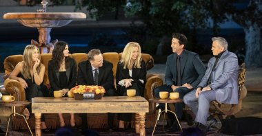 From the left Jennifer Aniston, Courteney Cox, Matthew Perry, Lisa Kudrow, David Schwimmer and Matt LeBlanc sit around the famous sofa from the television series "Friends" during the reunion special, with the water fountain from the show's intro in the background. (HBO Max via AP)