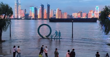 People stand next to an overflowing section of the Yangtze River at a riverside park following heavy rainfall in the region, in Wuhan, Hubei province, China May 26, 2021. (Photo by China Daily via Reuters)