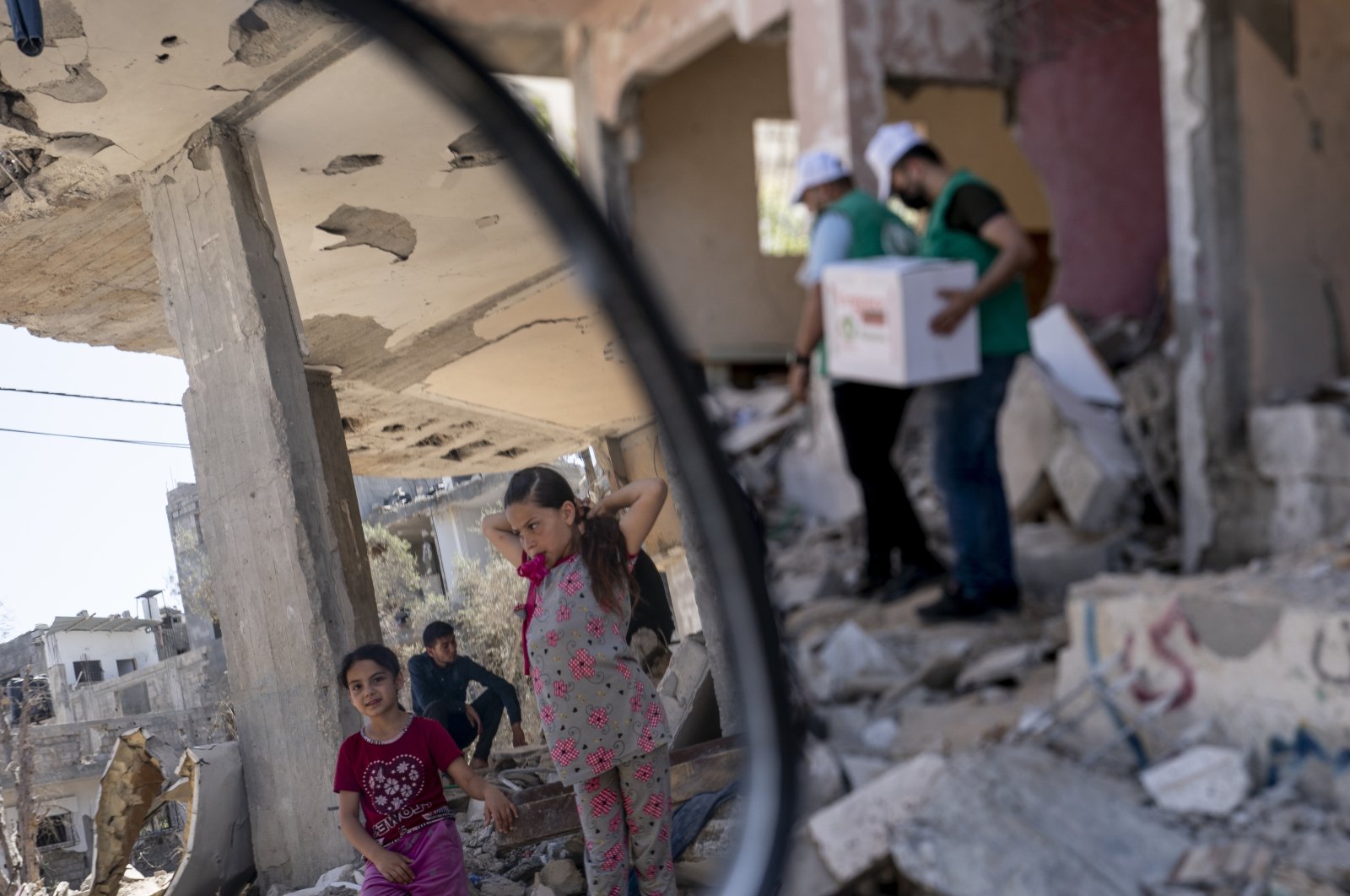 Children stand amid rubble from an Israeli airstrike as aid workers carry boxes through their neighborhood, days after a cease-fire that halted an 11-day war between Gaza's Hamas rulers and Israel, in Beit Hanoun, the Gaza Strip, Palestine, May 26, 2021. (AP Photo)