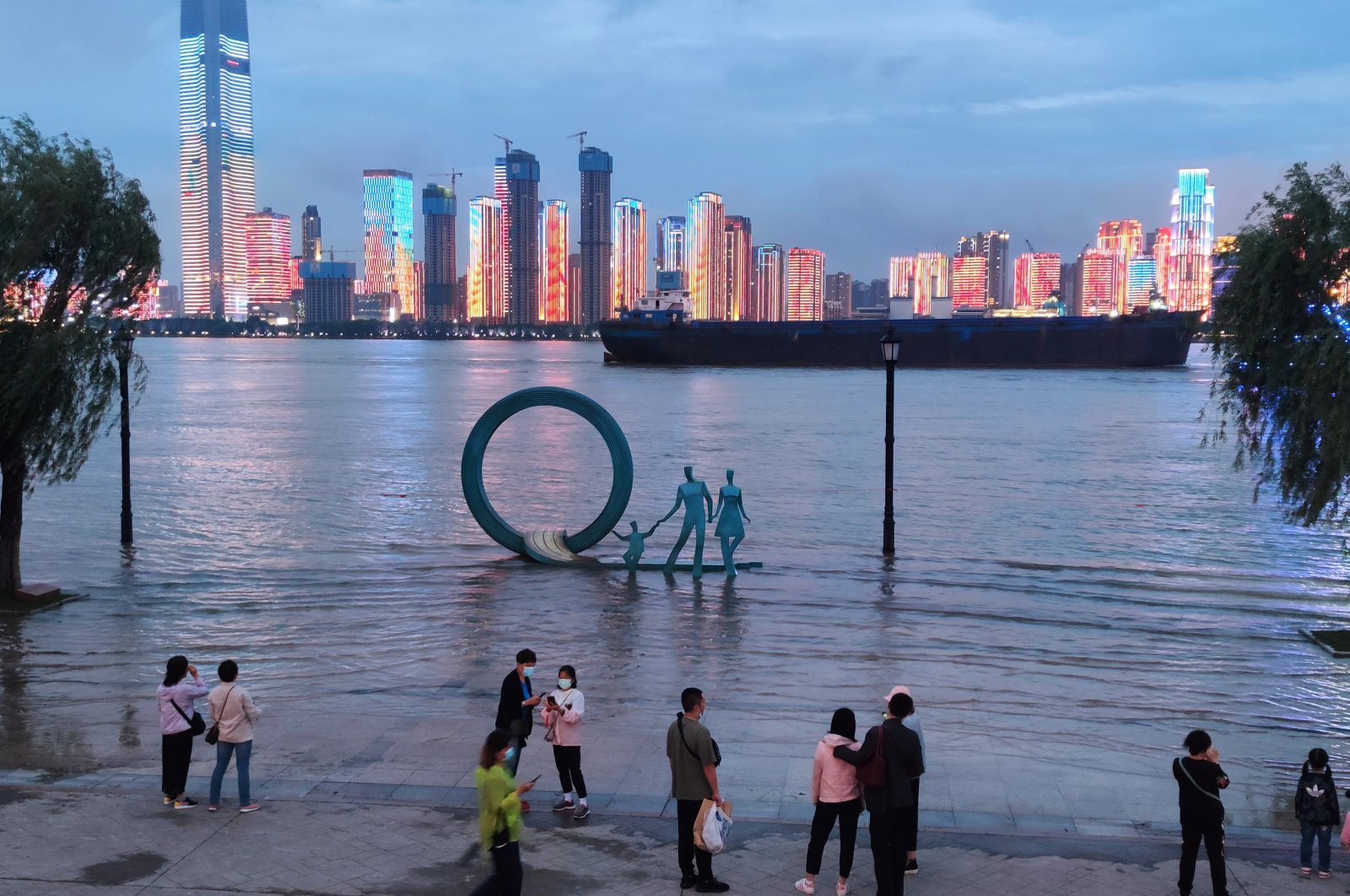 People stand next to an overflowing section of the Yangtze River at a riverside park following heavy rainfall in the region, in Wuhan, Hubei province, China May 26, 2021. (Photo by China Daily via Reuters)