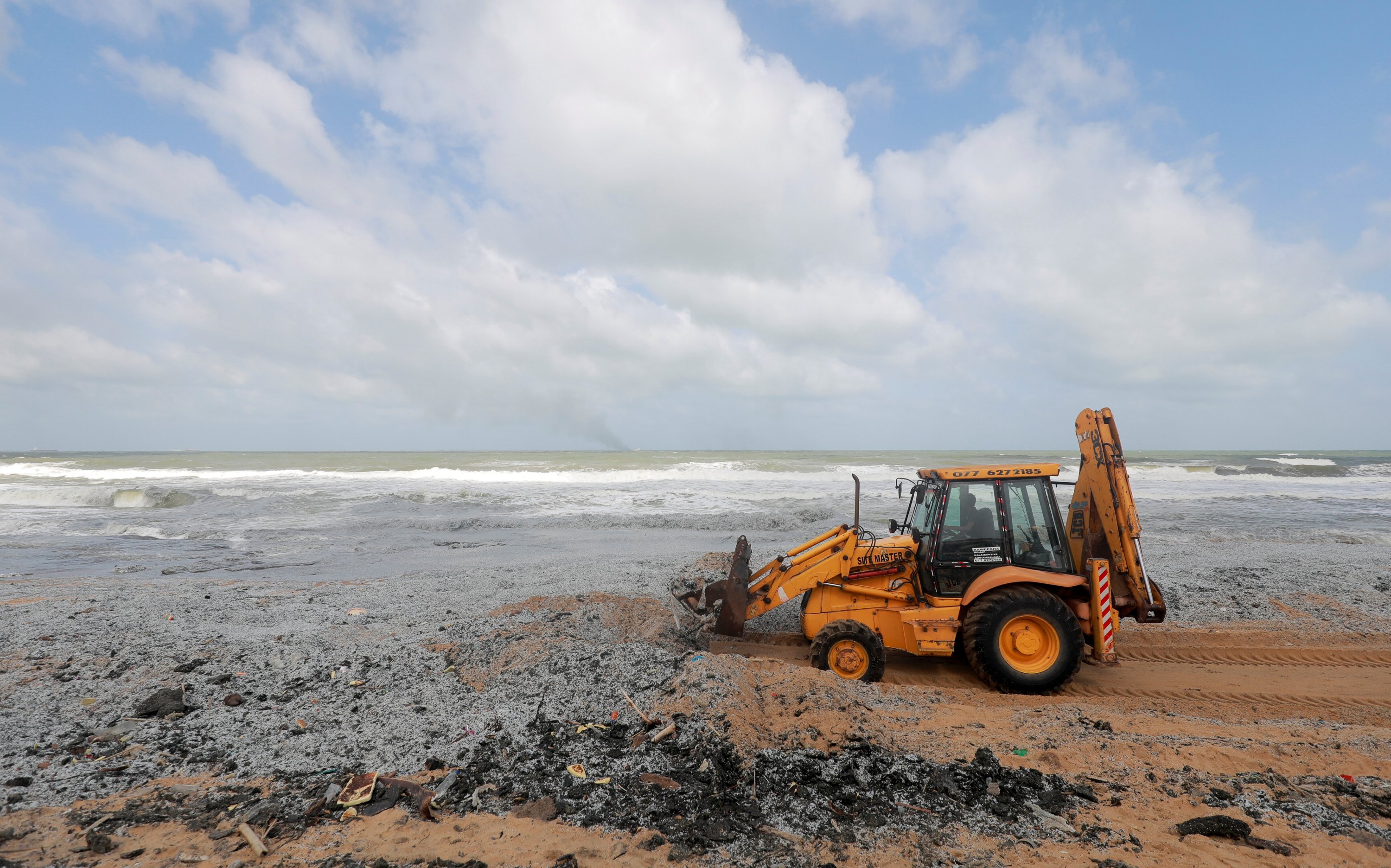 A backhoe loader collects debris washed onto a beach from the MV X-Press Pearl container ship, which caught fire off the Colombo Harbor, on a beach in Ja-Ela, Sri Lanka, May 28, 2021. (Reuters Photo)
