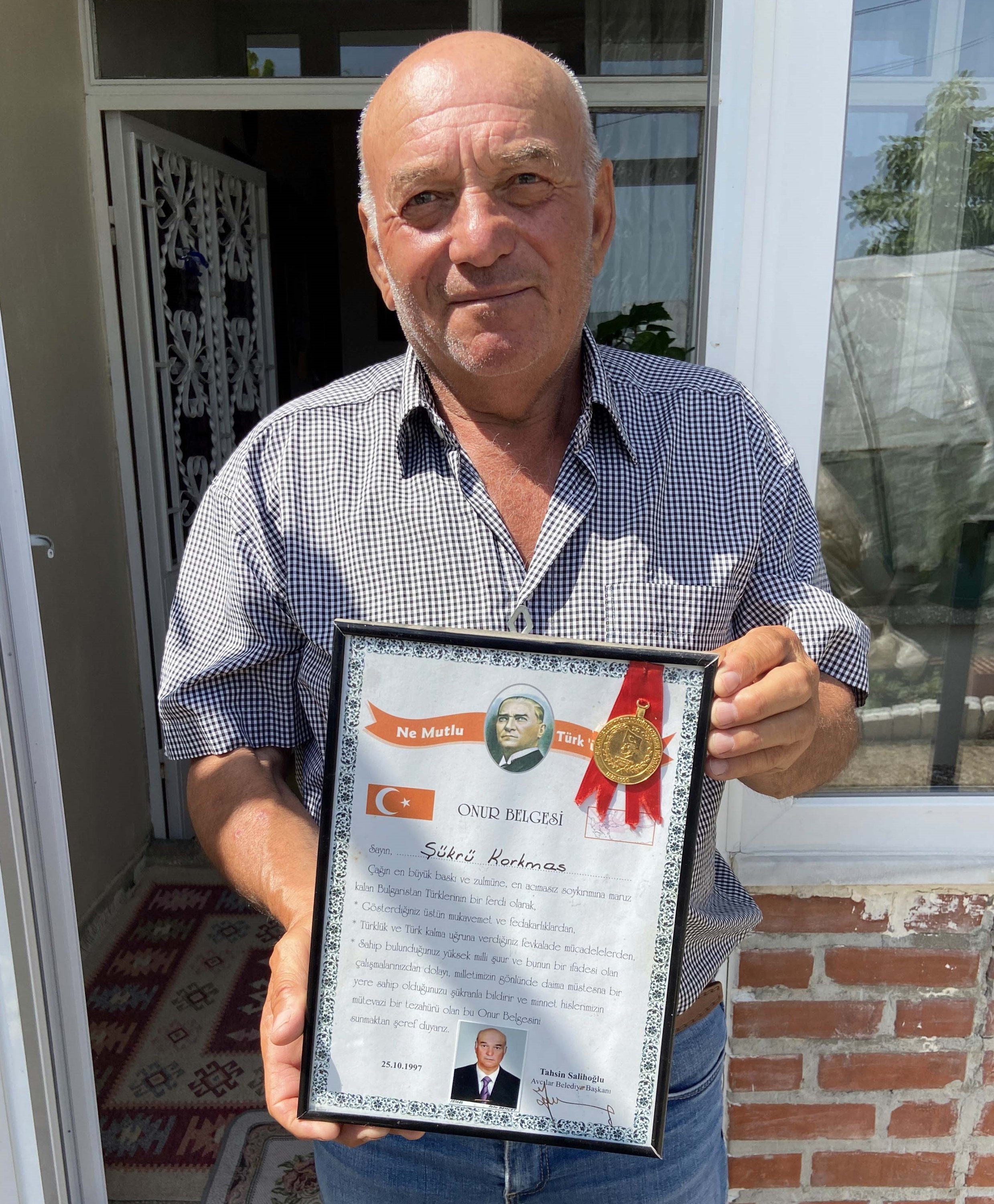 Şükrü Korkmaz holds up a 'certificate of honor' that he received when he arrived in Turkey after being forced to flee Bulgaria 32 years ago. He keeps the certificate in the best corner of his home. Edirne, Turkey, May 28, 2021. (Hakan Mehmet Şahin / Anadolu Agency)