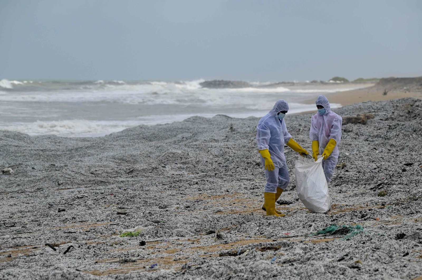 Sri Lankan Navy soldiers work to remove debris washed ashore from the Singapore-registered container ship MV X-Press Pearl, which has been burning for the ninth consecutive day in the sea off Sri Lanka's Colombo Harbor, on a beach in Colombo, May 28, 2021. (AFP Photo)