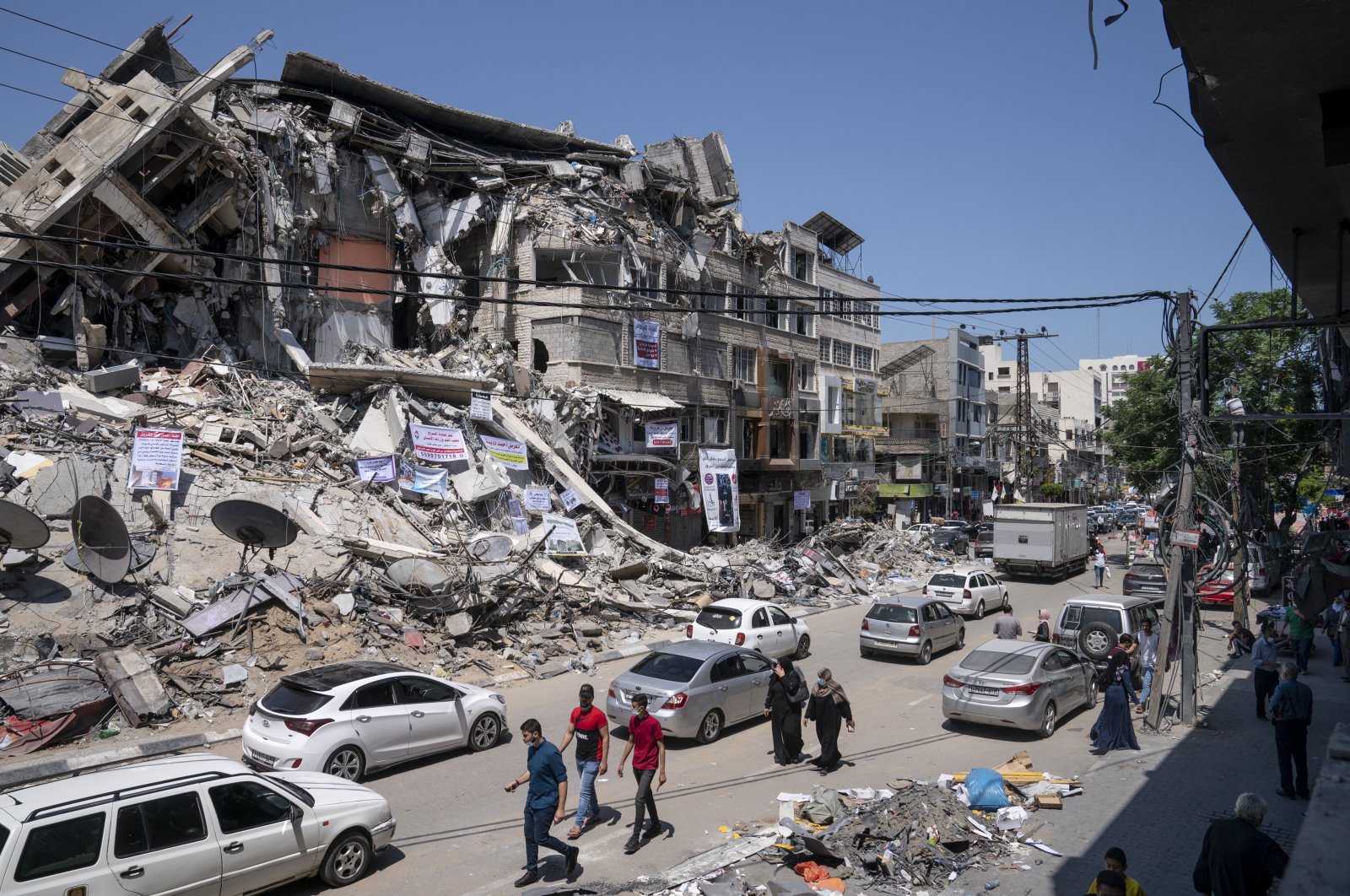 Motorists and pedestrians move past a building destroyed by an airstrike prior to a cease-fire that halted the 11-day war between Gaza's Hamas rulers and Israel in Gaza City, the Gaza Strip, May 25, 2021. (AP Photo)