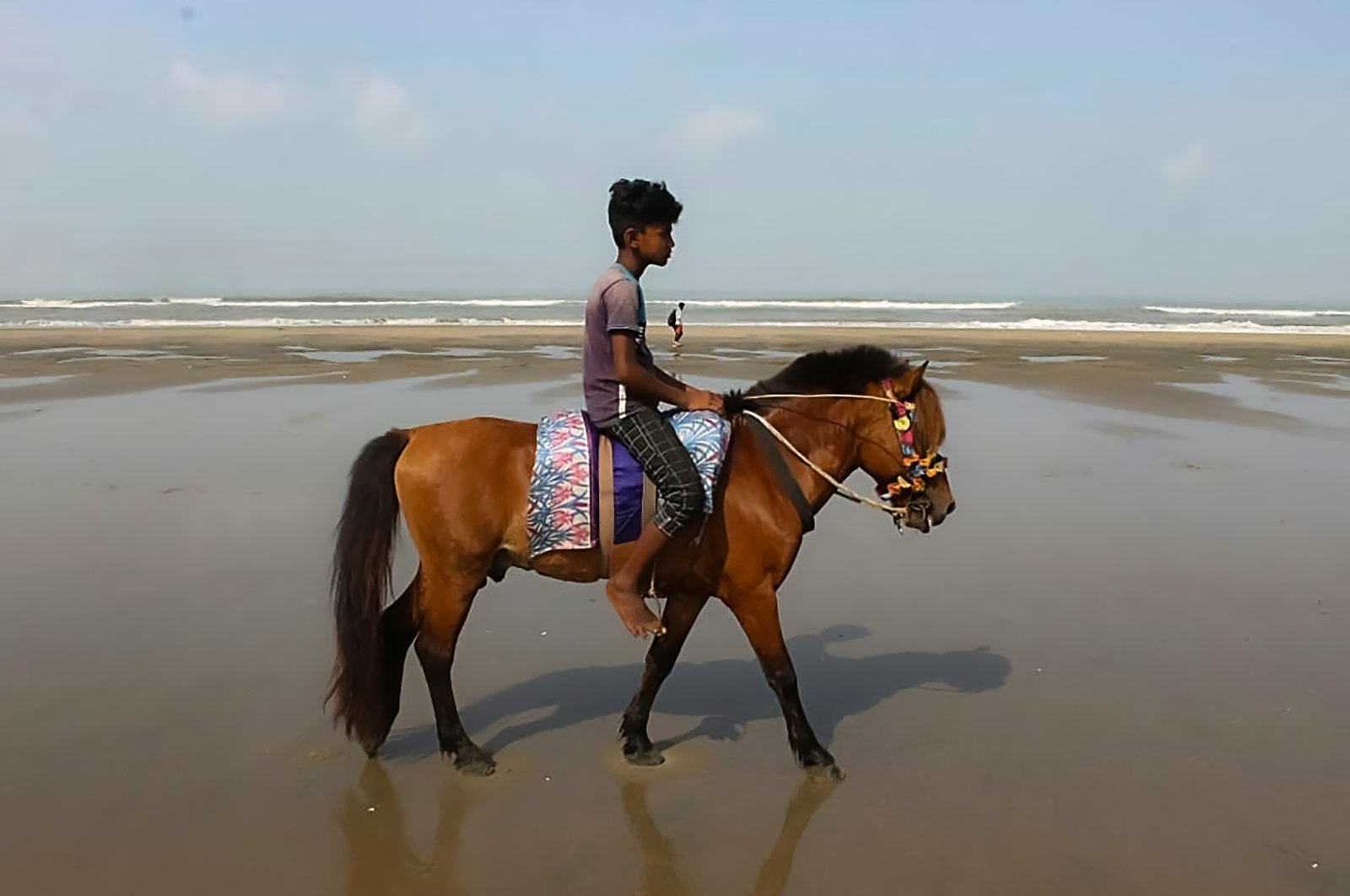 A youth waits for customers to ride on his horse, after some 21 horses have starved to death in the last month as COVID-19 lockdowns brought the country's most visited tourist spot to its knees, at a beach in Cox's Bazar, Bangladesh, May 29, 2021. (AFP Photo)