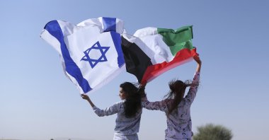 Israeli model May Tager (L) holds Israel's blue-and-white flag bearing the Star of David while next to her Anastasia Bandarenka, a Dubai-based model originally from Russia, waves the Emirati flag, during a photoshoot of Israeli fashion brand Fix, in Dubai, United Arab Emirates, Sept. 8, 2020. (AP Photo)