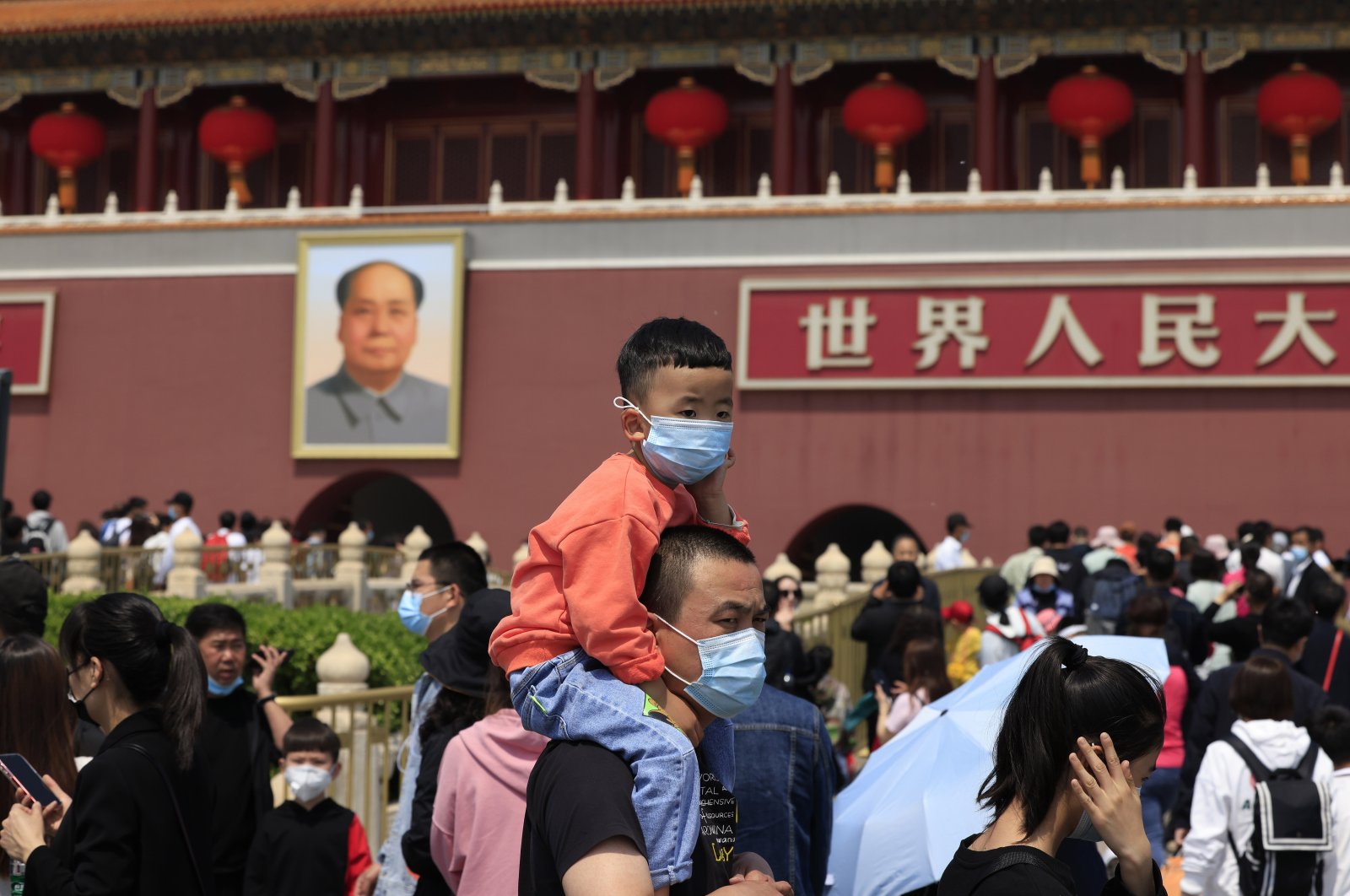 A man and child wearing masks visit Tiananmen Gate near the portrait of Mao Zedong in Beijing, China, May 3, 2021. (AP Photo)