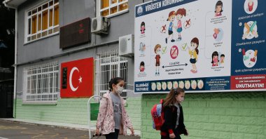 Children walk past a billboard about COVID-19 en route to school, in Izmir, western Turkey, June 1, 2021. (AA PHOTO)
