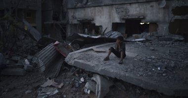 A boy sits on a destroyed building in a neighborhood heavily damaged by Israeli airstrikes, in Beit Hanoun, Gaza Strip, Palestine, May 31, 2021. (AP Photo)