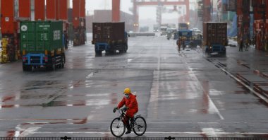 A worker rides a bicycle in a container area at a port in Tokyo, Japan, May 21, 2014. (Reuters Photo)
