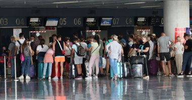 Tourists in masks standing with luggage wait in line at the Milas-Bodrum Airport, Bodrum, southwestern Turkey, Sept. 28, 2020. (Shutterstock Photo)