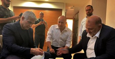 The head of the Arab Israeli conservative party Raam's Mansour Abbas (R) signing a coalition agreement with Israel's opposition leader Yair Lapid (L) and right-wing nationalist tech millionaire Naftali Bennett in Ramat Gan near the coastal city of Tel Aviv, Israel, June 2, 2021. (AFP Photo via United Arab List Raam)