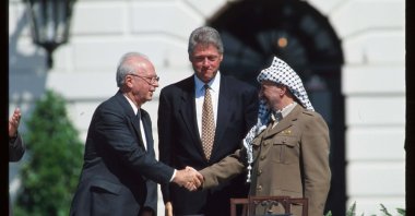 Palestine Liberation Organization (PLO) Chairperson Yasir Arafat (R) and Israeli Prime Minister Yitzhak Rabin (L) shake hands after the signing of the Oslo Accords in front of U.S. President Bill Clinton, Washington, D.C., U.S., Sept. 13, 1993. (Photo by Getty Images)