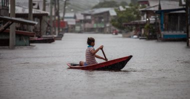 A girl paddles a small canoe through flooded streets n Anama, Amazonas, Brazil, May 23, 2021. (EPA Photo)