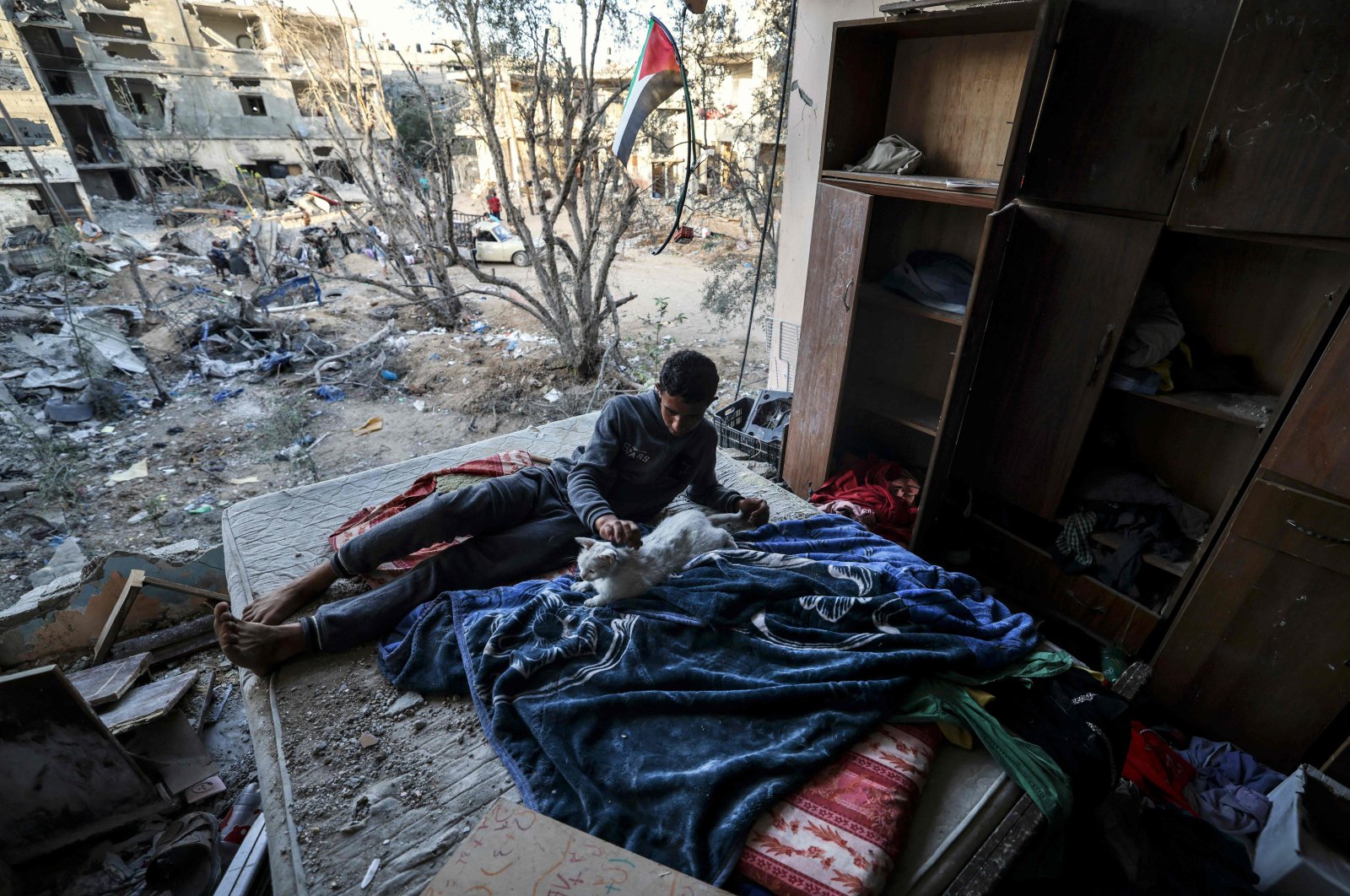 A young Palestinian pets a cat in a building heavily damaged during recent Israeli strikes more than a week after a cease-fire brought an end to 11 days of hostilities between Israel and Gaza rulers Hamas, Beit Hanun, northern Gaza Strip, June 1, 2021. (AFP Photo)