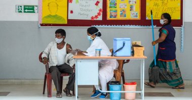 A health worker inoculates a man with a dose of the Covishield Covid-19 coronavirus vaccine during a vaccination drive for auto-rickshaw and taxi drivers at a school in Hyderabad, India, June 4, 2021. (AFP Photo)
