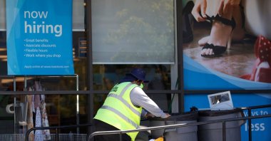 A worker pushes a cart by a 'Now Hiring' sign outside of a store in Sausalito, California, U.S., June 3, 2021. (AFP Photo)

