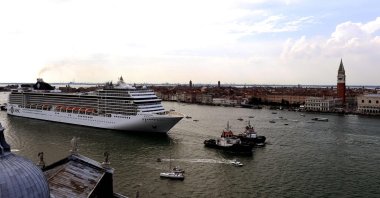 Tugboats escort the MSC Orchestra cruise ship across the basin past the Bell Tower and the Doge's Palace as it leaves Venice, Italy, June 5, 2021. (AFP Photo)