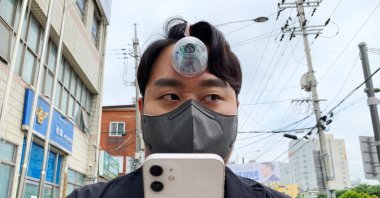 South Korean industrial designer Paeng Min-wook showcases a robotic eye, called "The Third Eye," on his forehead as he uses his mobile phone while walking on the street, in Seoul, South Korea, March 31, 2021. (Reuters Photo)