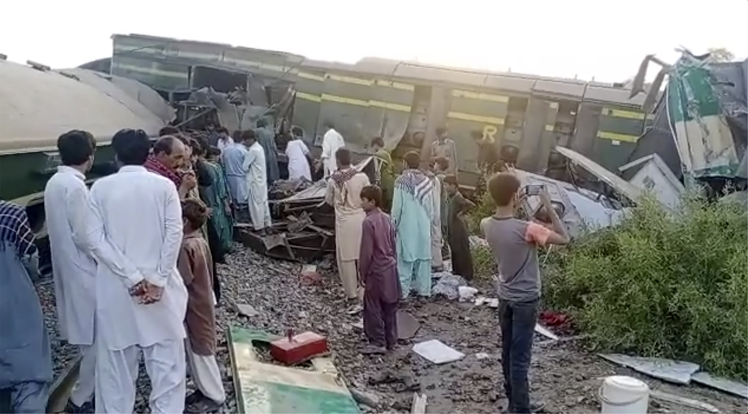 In this image from a video, people gather at the site of a train collision in Ghotki, Pakistan, on Monday, June 7, 2021. (AP Photo)