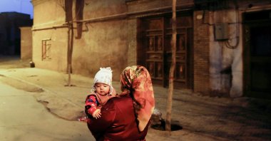 A woman carries a child at night in the old town of Kashgar, Xinjiang Uighur Autonomous Region, China, March 23, 2017. (Reuters Photo)